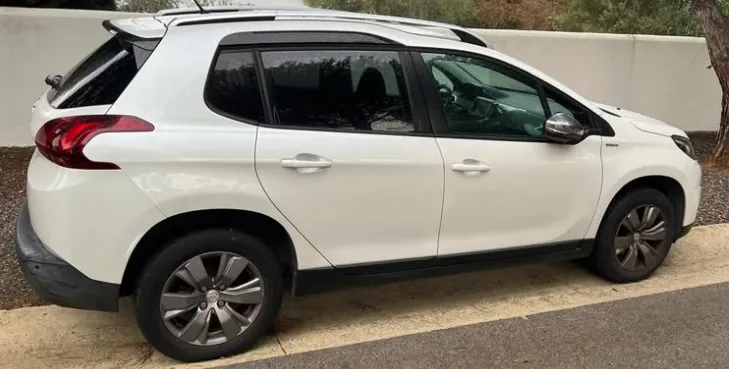 A white Peugeot 2008 parked on a quiet street in Marbella, showcasing its compact SUV design, raised ride height, modern body lines, and practical roof rails. This versatile crossover is a popular choice for travelers looking to rent a Peugeot 2008 in Marbella, offering comfort, fuel efficiency, and enough space for exploring the Costa del Sol. The calm outdoor setting highlights its practicality for anyone searching to rent a car in Marbella.