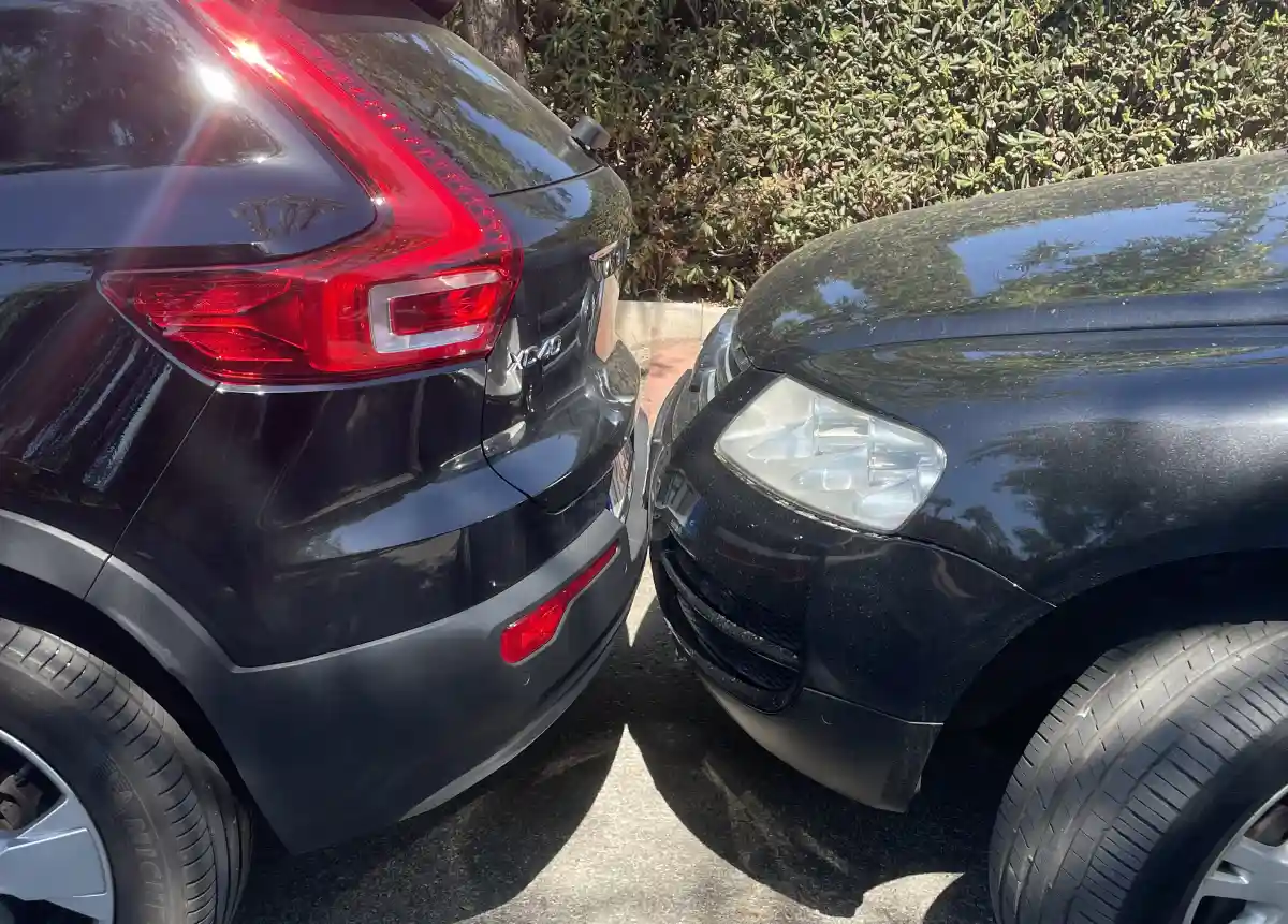 Two cars parked extremely close together in Marbella showing typical Spanish parking style