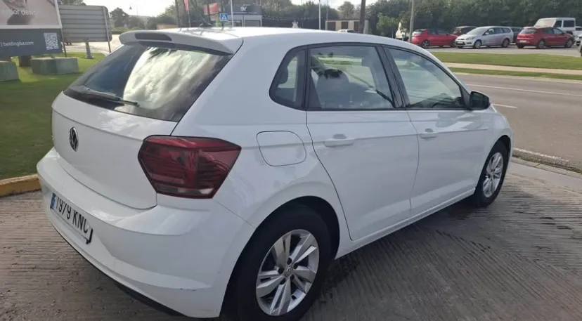 A white Volkswagen Polo parked beside a main road in Marbella, showing its compact hatchback design, modern rear lights, and clean, well-maintained exterior. The practical size and efficient build make it a popular choice for travelers looking to rent a Volkswagen Polo in Marbella, offering comfort, reliability, and excellent fuel economy for exploring the Costa del Sol. The bright outdoor setting highlights the car's versatility and supports content related to renting a car in Marbella.
